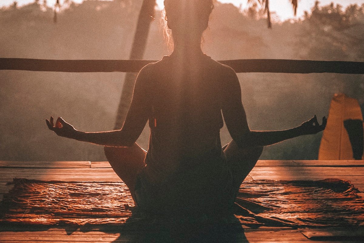 A figure meditating at sunrise